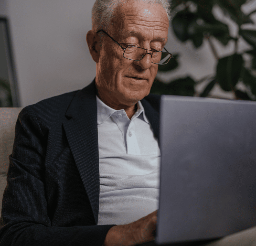 An elderly man with a laptop, learning about the importance of a “date-of-death” appraisal
